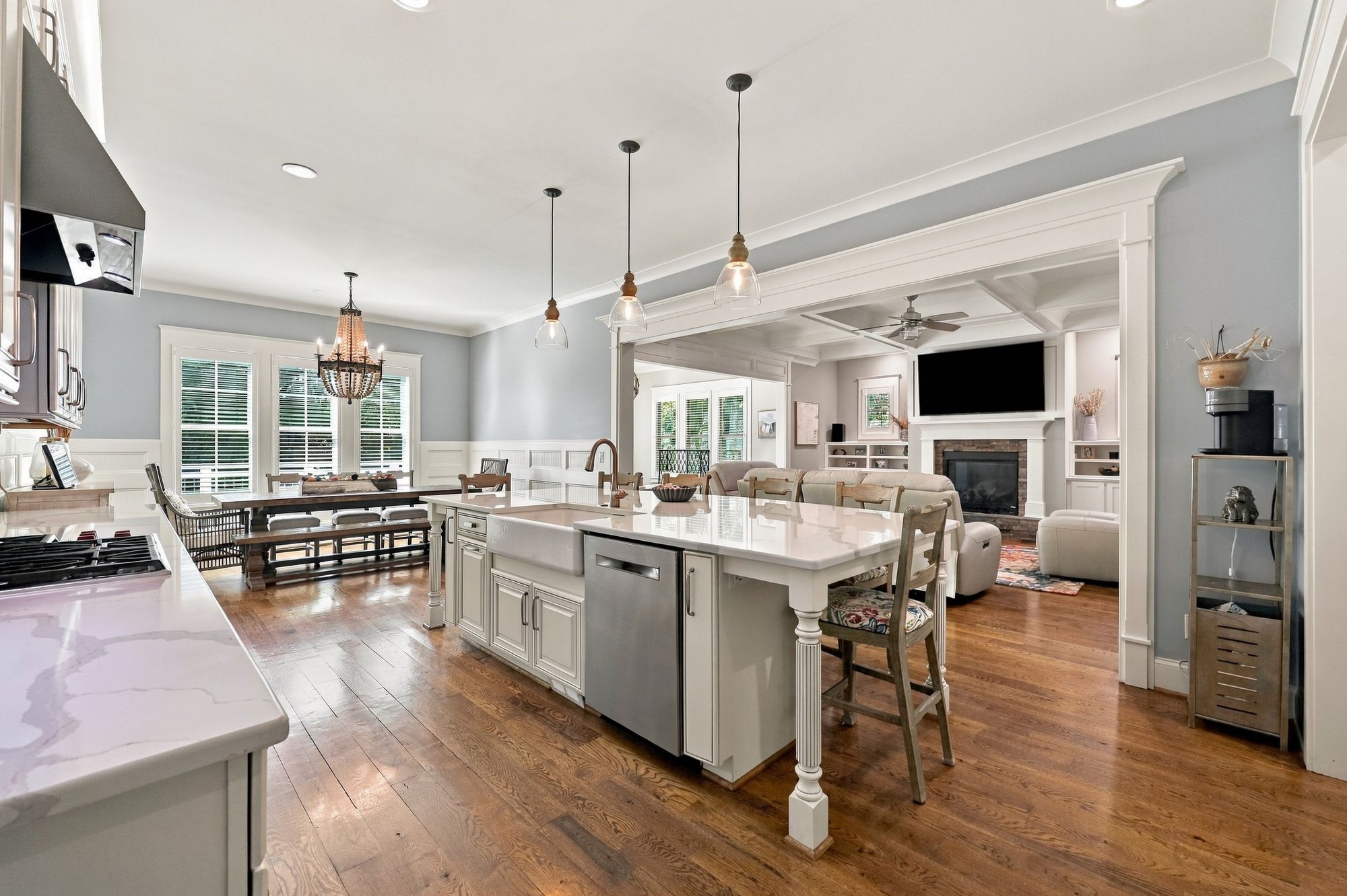 Chef’s kitchen with quartz island and pendant lighting, open to the family room